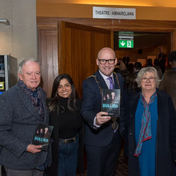 four people posing with a book