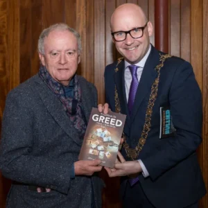 Two men holding a copy of the book Fountain of Greed at a launch event in Dublin.
