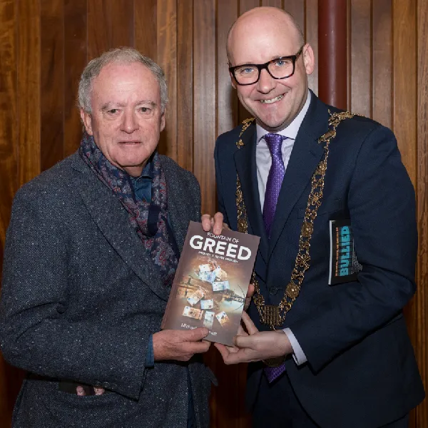Two men holding a copy of the book Fountain of Greed at a launch event in Dublin.
